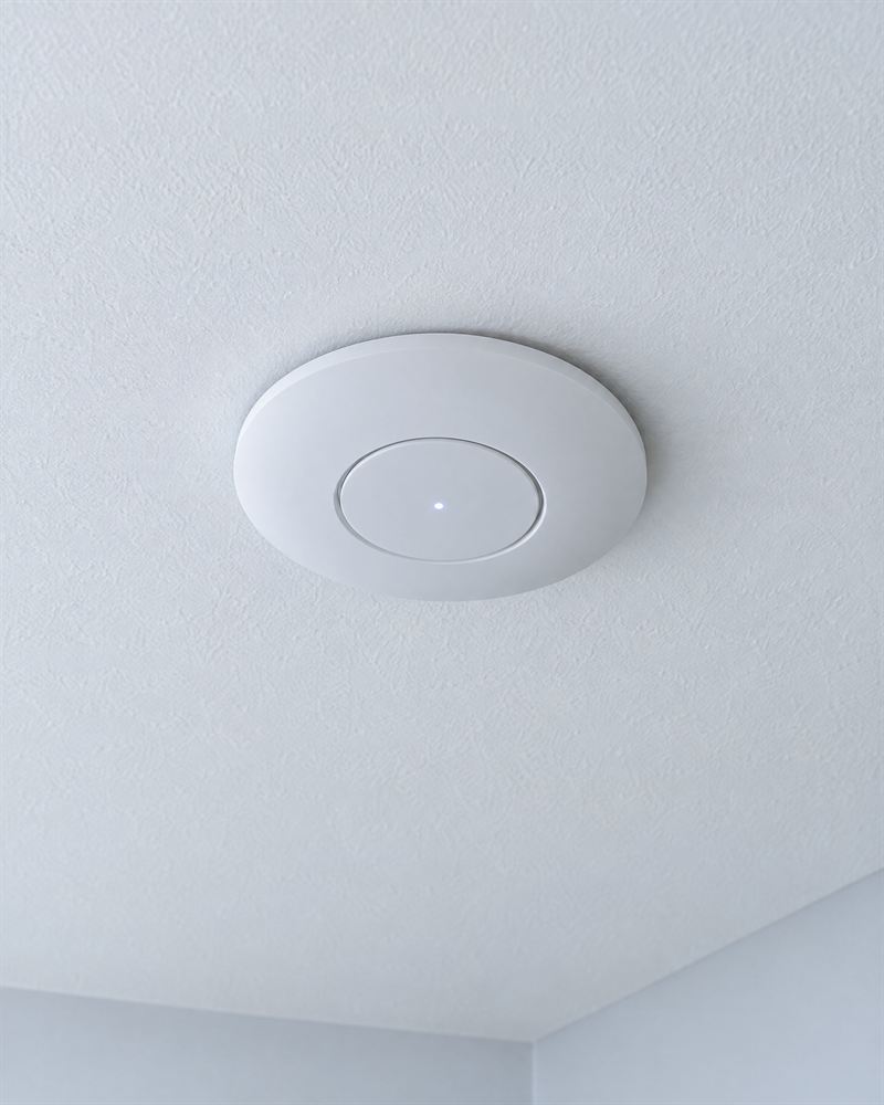 Un punto de acceso wifi blanco instalado en el techo.